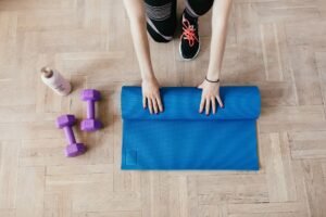 Dumbbells and an exercise mat on a wooden floor at home