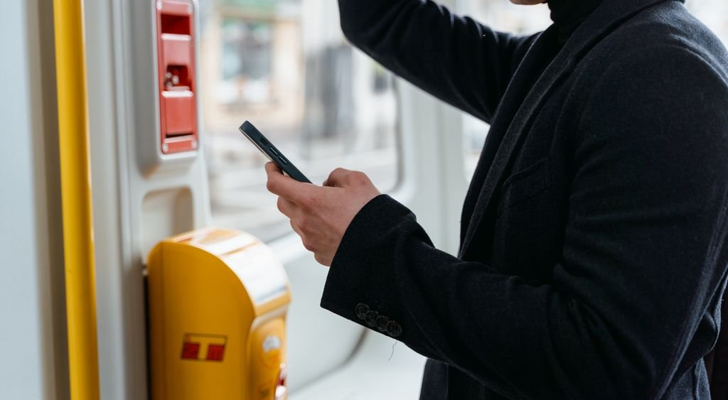 Close view of hands holding a smartphone on board a moving tram