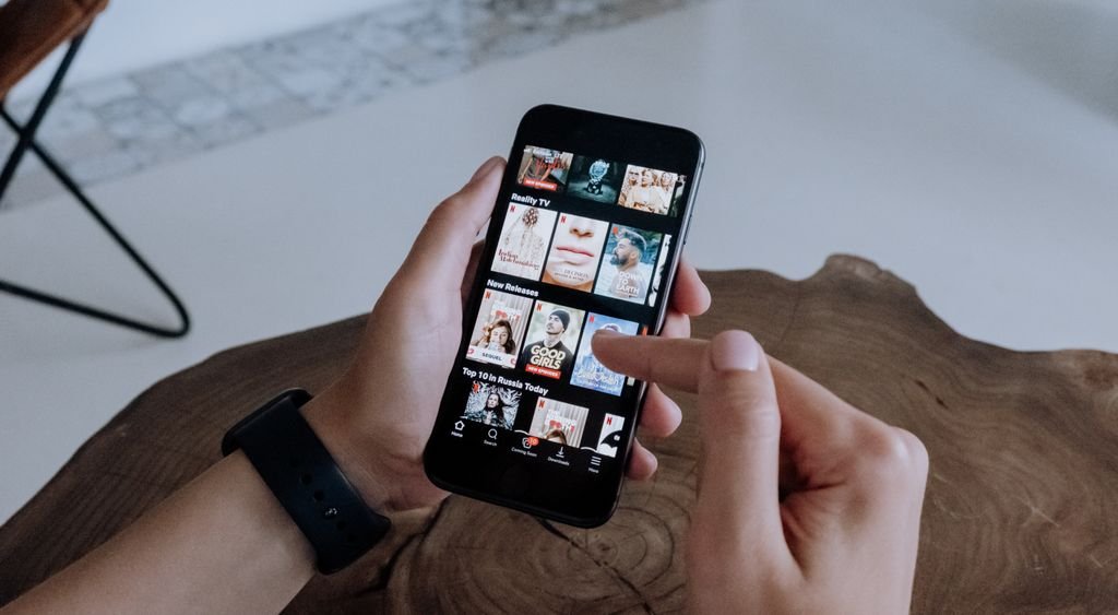 Mains tenant un smartphone affichant un catalogue de vidéos à la demande
