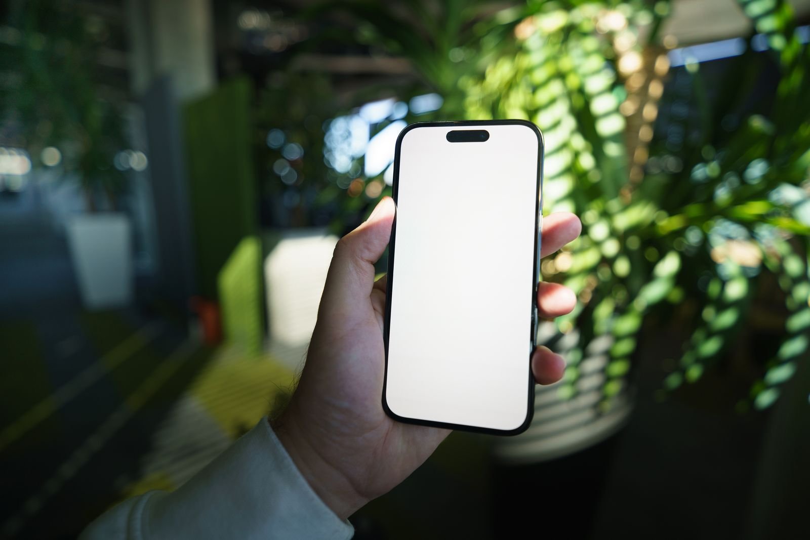 Hand holding a smartphone with a blank screen