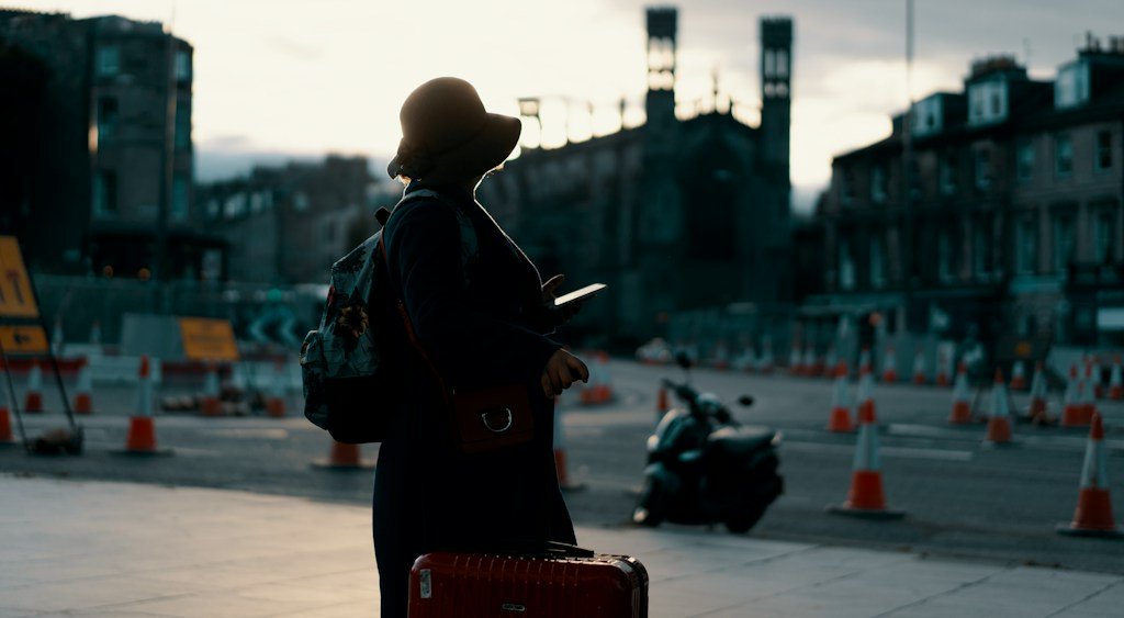 Traveller with a phone in a city square at dusk