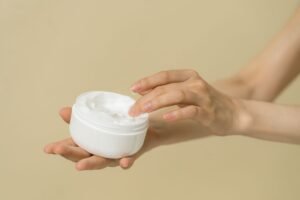 Hands holding an open jar of rich body cream